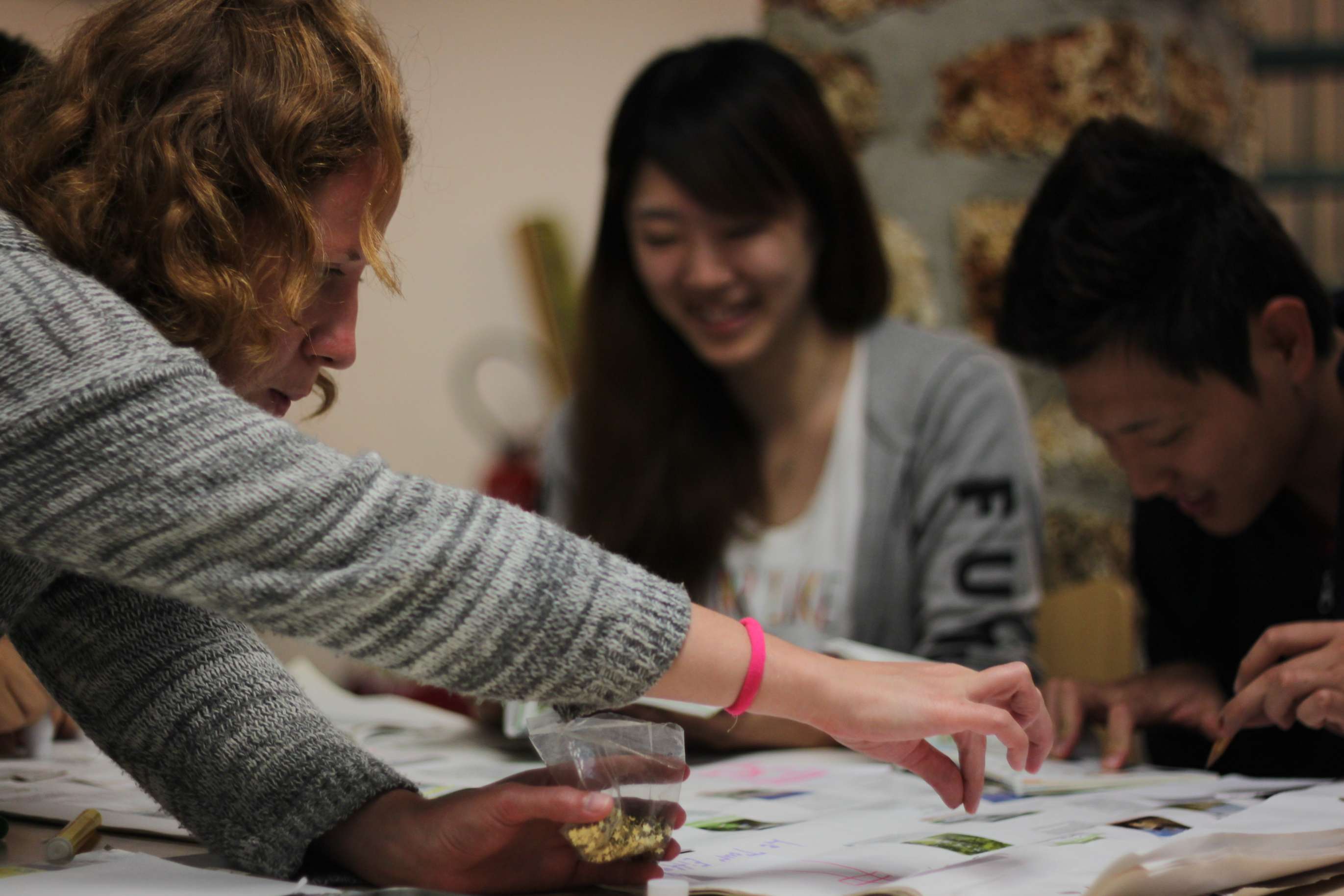 Three people work at a table preparing items for an activity.