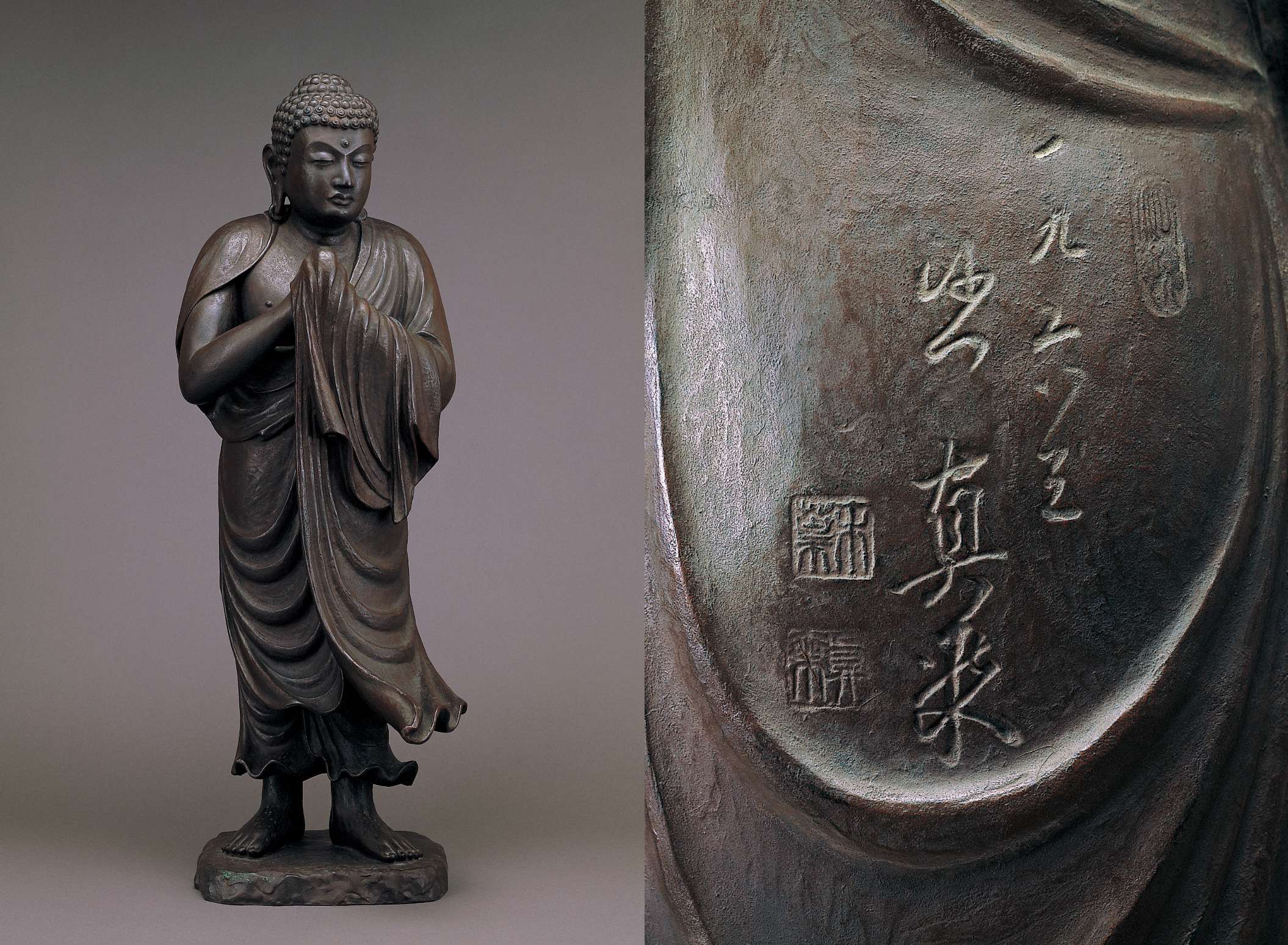 A dark-hued matte statue of barefoot, standing Buddha, gaze turned slightly aside as if giving attention to someone; the movement of robes draped over hands in prayer gesture suggest a windy scene (left). A close-up of the back of the statue showing Japanese calligraphy and stamps etched into a smooth portion of the metal between the falling drapery of the Buddha’s robes (right).