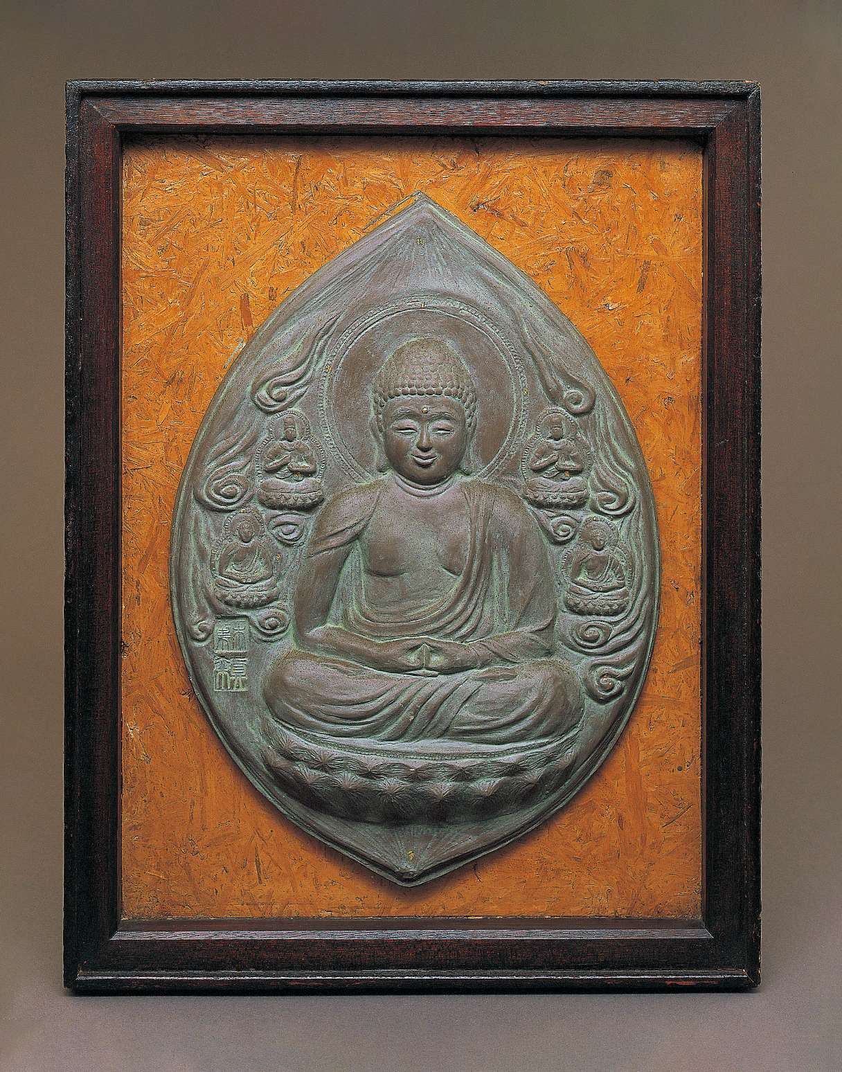 An upright almond-shaped grayish relief of a buddha sitting cross-legged atop a lotus seat with his hands in meditation posture, surrounded by clouds and four smaller buddhas.